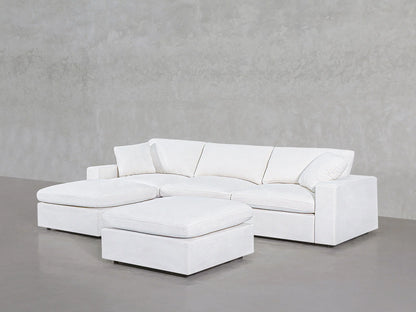 The 4-Seat Modular Chaise Sectional with Ottoman, featuring a modern white design, is arranged against a light gray textured wall. Its clean lines and plush cushions give the seating a minimalist and spacious look.