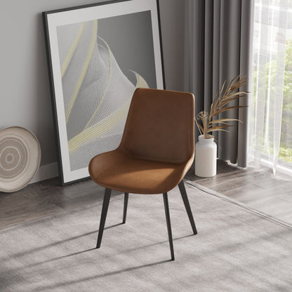 A modern room includes a Modern Dining Chair with brown leather and black metal legs on a gray carpet. A framed abstract artwork leans against the wall, while a vase of dried plants is nearby. Sheer curtains adorn the window in the background.