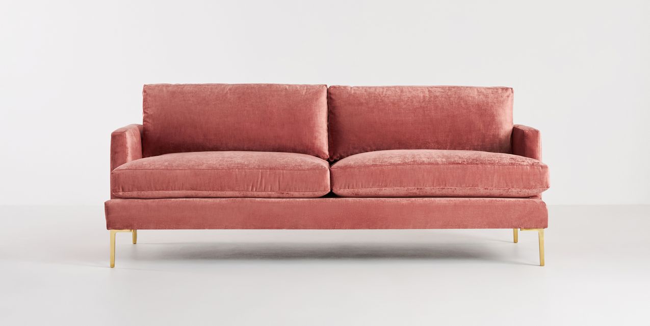 The Bowen 91" Sofa, featuring a contemporary design in pink velvet with two large seat cushions and two back cushions, rests against a plain white background. It is supported by elegant gold legs.