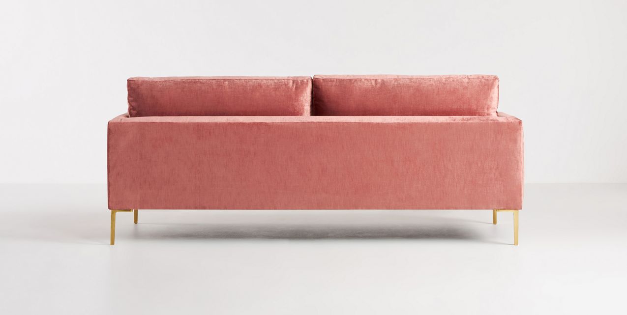 The Bowen 91" Sofa, featuring a pink velvet finish and rectangular backrest, is displayed against a plain white background. It boasts a minimalist design with sleek, gold metal legs.