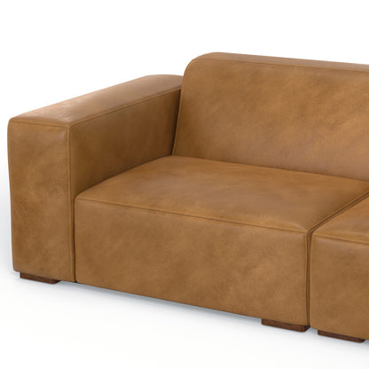 Brown leather sectional sofa with wide armrest and smooth finish, shown against a plain background. The design is modern and minimalist, featuring clean lines and a boxy shape.