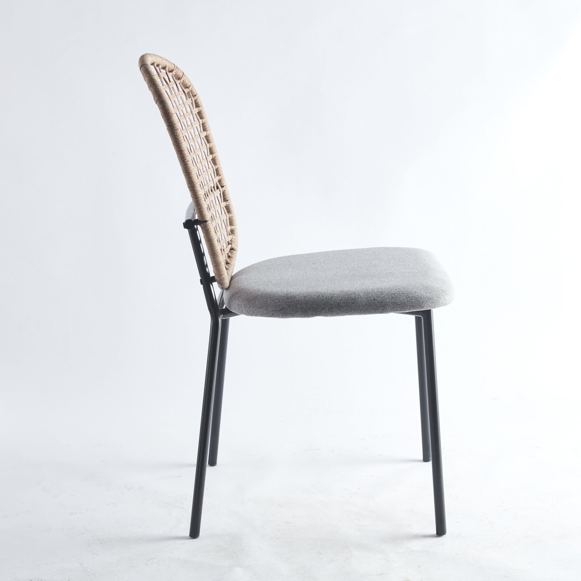 Side view of a chair from the 5 Piece Dining Set featuring a woven rattan backrest, a grey cushioned seat, and black metal legs against a light background.