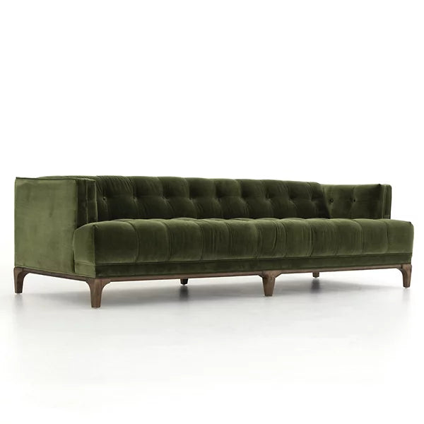 The Dylan Sofa by Four Hands, featuring a modern design with green velvet tufting and wooden legs, is elegantly displayed in a minimalist indoor setting.