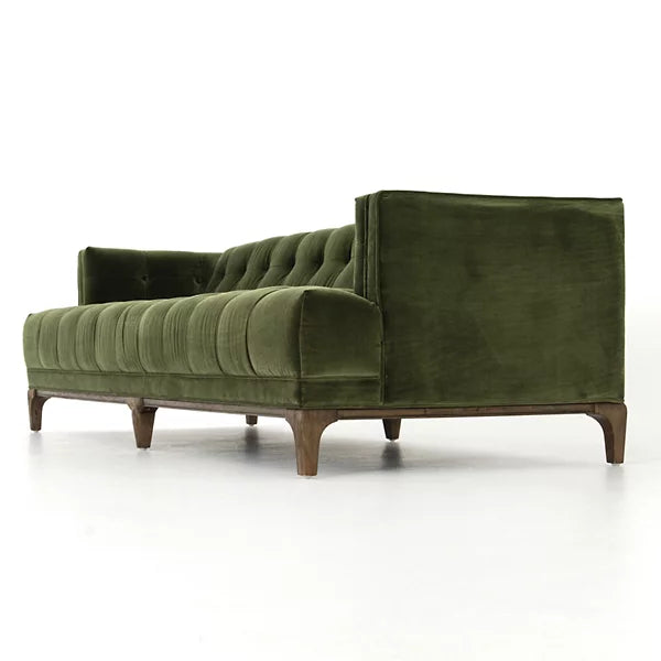 The Dylan Sofa by Four Hands is featured against a white background, showcasing its vibrant green velvet upholstery and tufted design. The sofa's modern aesthetic is enhanced by square armrests, a low backrest, and elegant wooden legs.