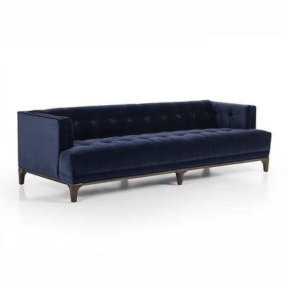 The Dylan Sofa by Four Hands is a sleek, dark blue velvet piece with a modern design, featuring button-tufted seating and wooden legs, set against a white background.