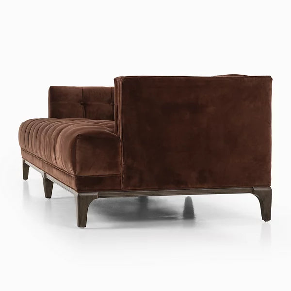 The Dylan Sofa by Four Hands, a brown velvet sectional with plush cushions and a modern design, is set against a white background. It features a tufted backrest, solid black legs, and showcases an L-shaped configuration.