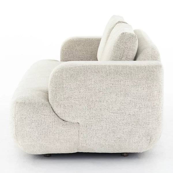 A side view of the Benito Sofa by Four Hands, showcasing its modern design with light gray fabric, rounded armrests, and a plush backrest against a plain white background. The minimalist and contemporary style emphasizes both comfort and elegance.