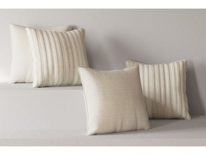 On the Maggie Sofa, four beige throw pillows made of textured fabric are neatly arranged. Two of the pillows feature a ribbed design, while the other two have a smooth texture. The surrounding decor complements this with matching neutral tones, forming a serene and minimalist ambiance.