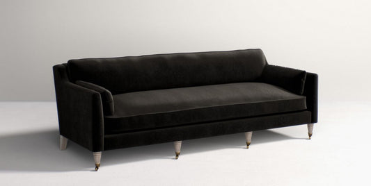 The Leonelle Sofa features a sleek black velvet upholstery with wooden legs, set against a plain white background. It boasts a modern design with plush cushions and a minimalist aesthetic.