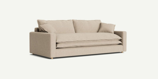 The Meriwether Sofa is a beige, modern piece featuring square armrests and a plush seat, complemented by multiple matching cushions. It stands on short, round wooden legs and is showcased against a plain white background.