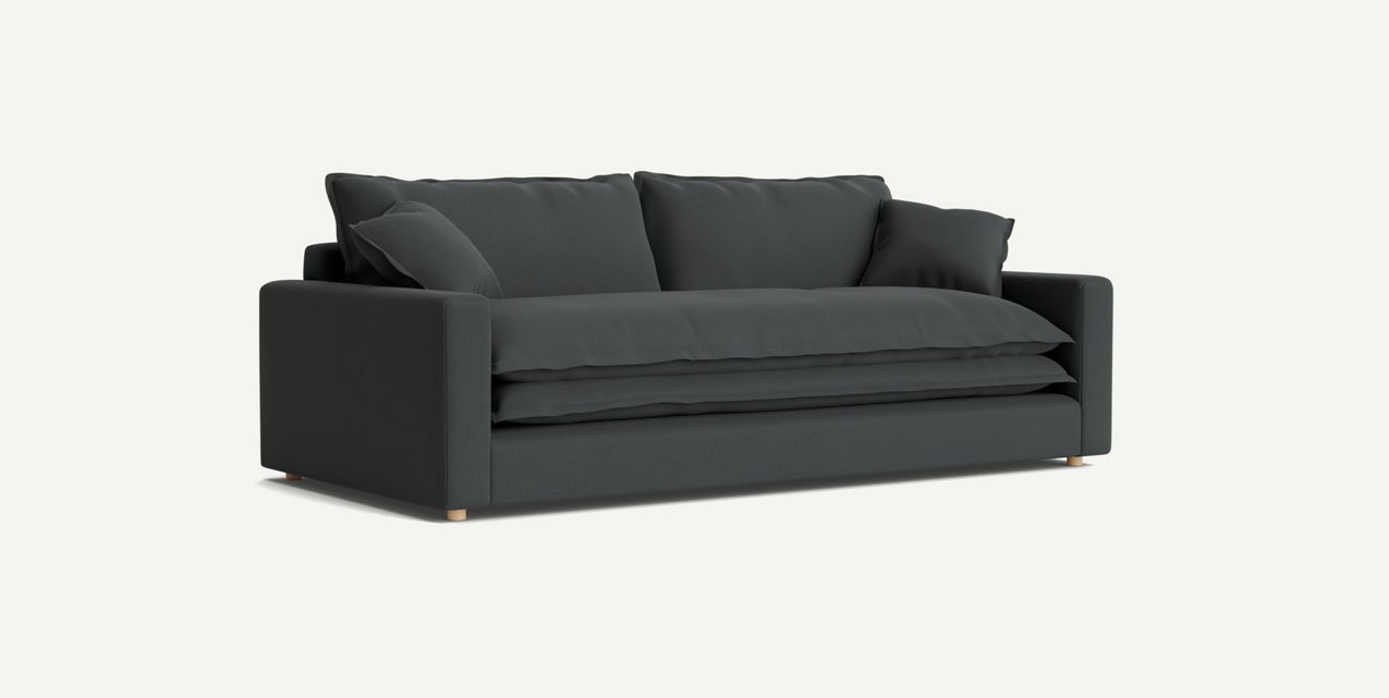 The Meriwether Sofa, showcasing a modern dark green design with clean lines and plush cushions, stands out against a plain light background. This minimalist piece features wooden legs and incorporates three cushioned backrests for enhanced comfort.