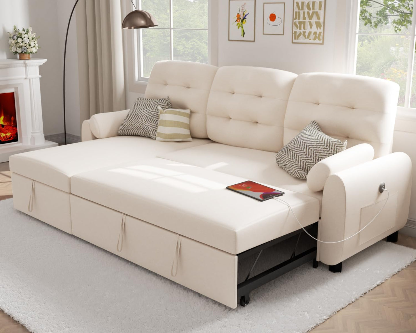 A cozy living room showcases the Ucloveria 87" Sectional Sleeper Sofa Bed with cushioned seats and pillows in a cream color. Beside it stands a modern lamp, while a tablet is conveniently plugged into the sofa's charging station. The warm ambiance of the fireplace enhances the space, accentuated by art hanging on the walls.