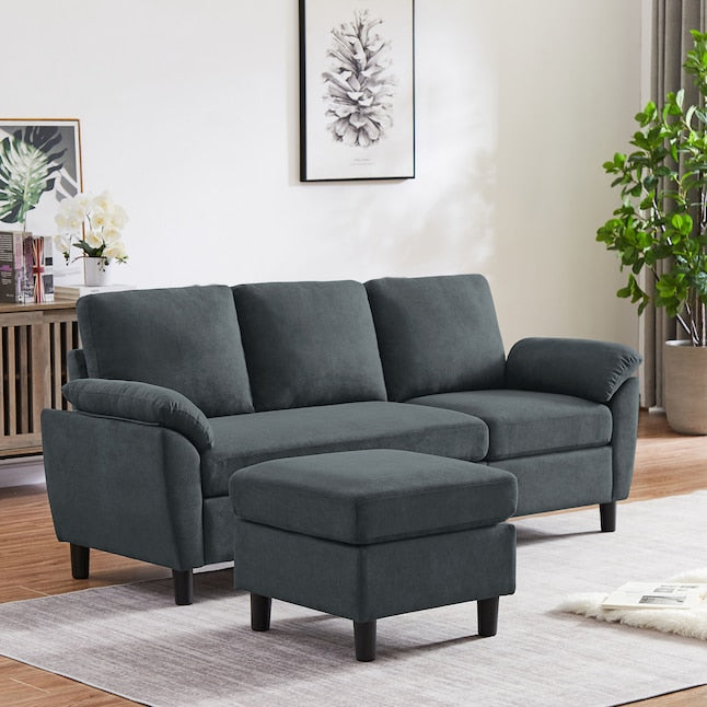 A modern living room showcasing a Jarenie Casual Dark Grey Linen Sectional paired with a matching ottoman on a light rug. A potted plant sits on the floor, while wall art displays a pinecone design. A console table holds decorative items and features a white orchid.