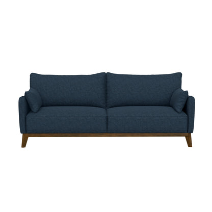 The Varia sofa in dark blue boasts a minimalist design with two back cushions, two side pillows, and wooden legs, set against a plain white backdrop.