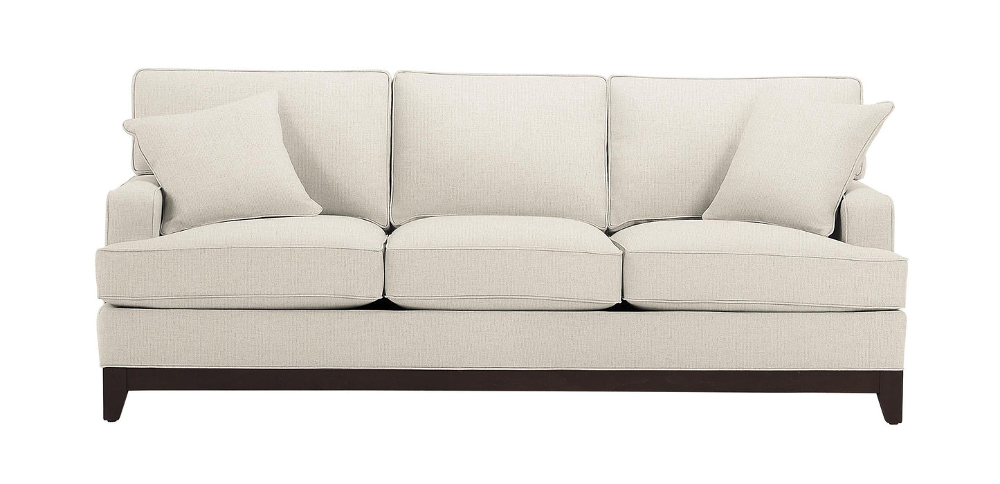 Introducing the Arcata Sofa, Quick Ship: a light gray, three-cushion sofa with dark wooden legs. It comes with two matching throw pillows, offering a simple and elegant design. The sofa exudes comfort against a plain white background.