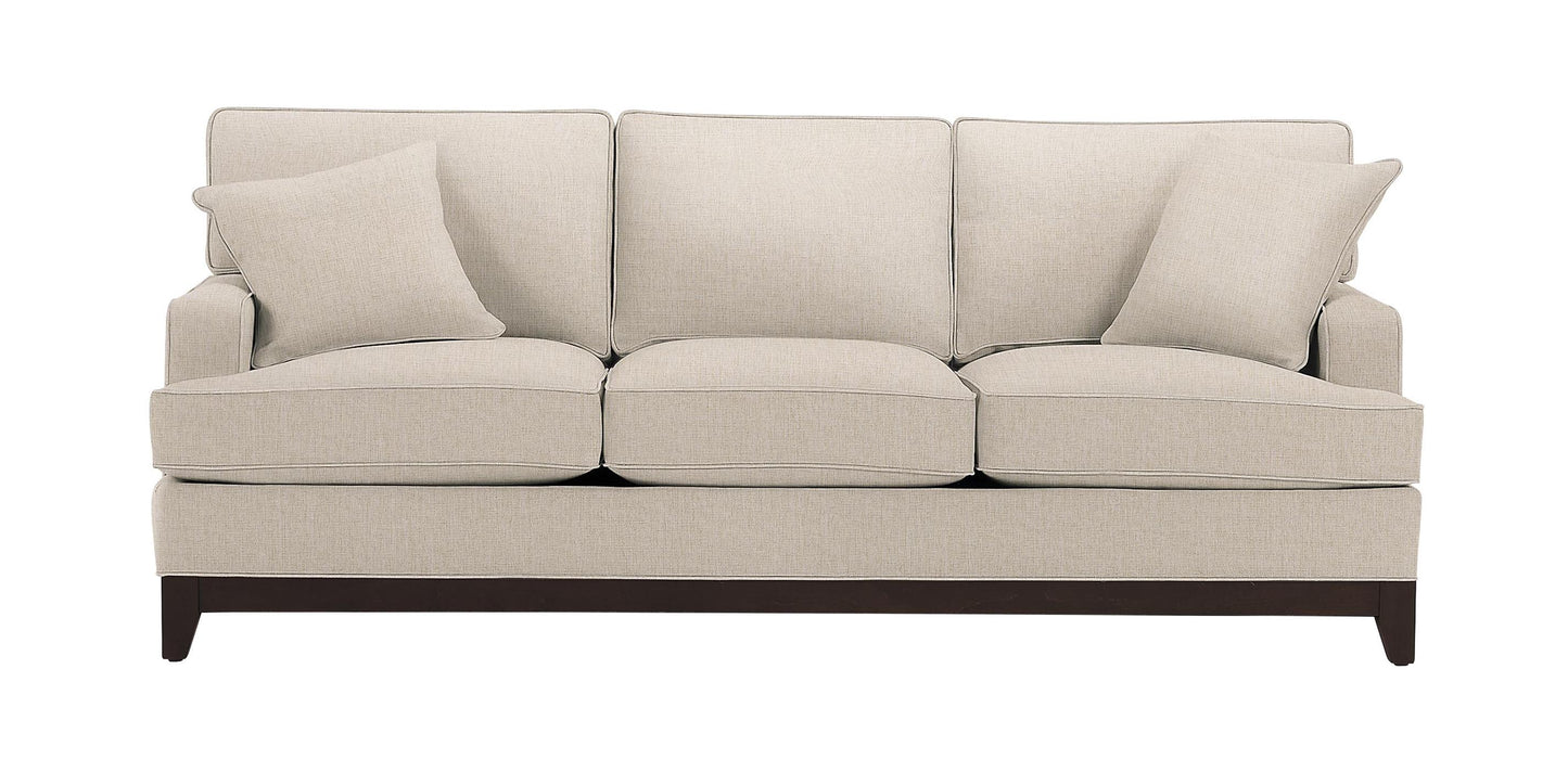 The Arcata Sofa, Quick Ship is a beige three-seater couch complete with matching cushions, plush backrests, and seat cushions. It boasts dark wooden legs and a clean, modern design.