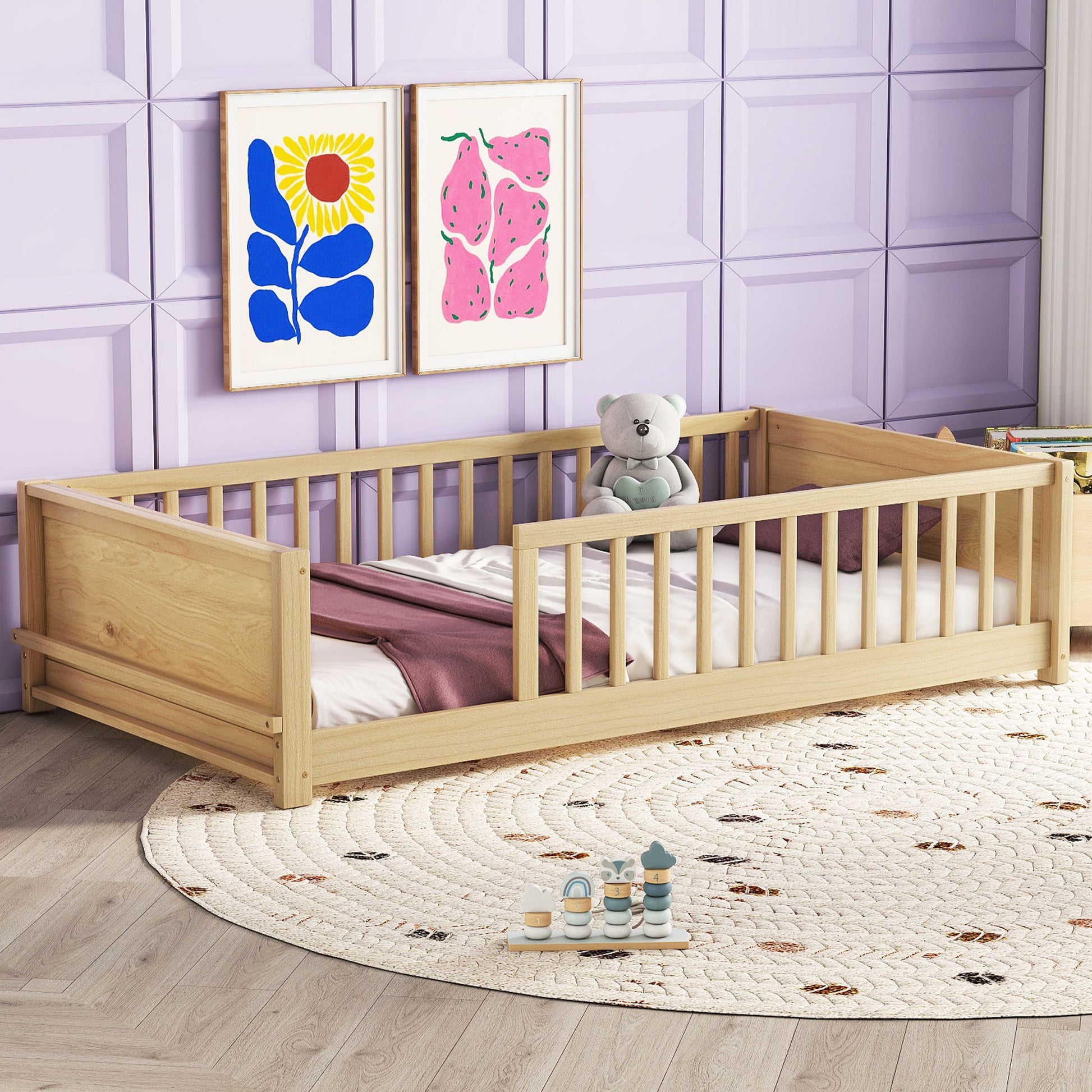 The Floor Platform Bed With Built-In Book Storage Rack sits on a round, patterned rug. It features a white mattress, mauve blanket, and teddy bear. The wall is light purple with geometric panels and colorful artwork above the bed.