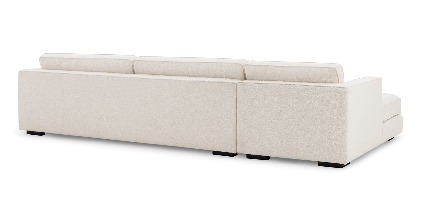 The Architect 133" Fabric Sofa Sectional Left in Blanc Boucle is depicted from a rear view, showcasing its cream-colored, rectangular silhouette with three cushioned backrests. Its minimalist design is complemented by sleek black square legs against a plain white backdrop.