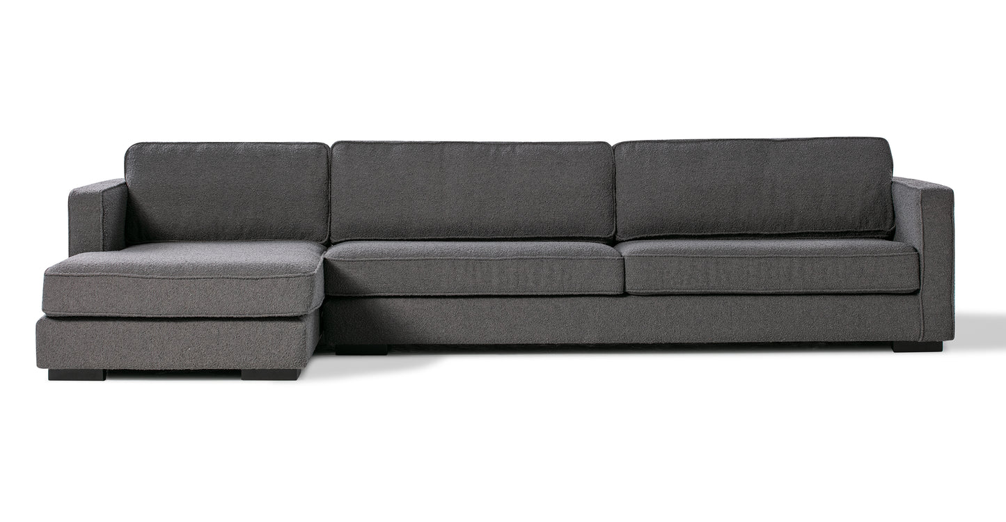 Introducing the Architect 133" Fabric Sofa Sectional Left in Blanc Boucle—a sophisticated dark gray sectional sofa that includes a left-side chaise and three seat cushions. Perfect for enhancing a minimalist or contemporary living area, this piece stands out beautifully against a plain white background.