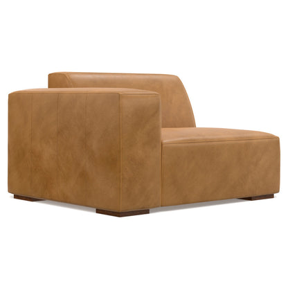 A wide tan leather lounge chair with a low back and arms, placed on small dark wooden legs. The design is minimalist with smooth, clean lines and a boxy shape, giving it a modern and sophisticated appearance.