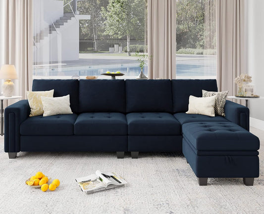 A modern living room featuring a large Belffin Reversible Sectional Convertible Storage in dark blue, facing a window. The sectional is embellished with light-colored pillows. On the light-colored carpet, there's a magazine and fruit. In the background, a pool and trees are visible.