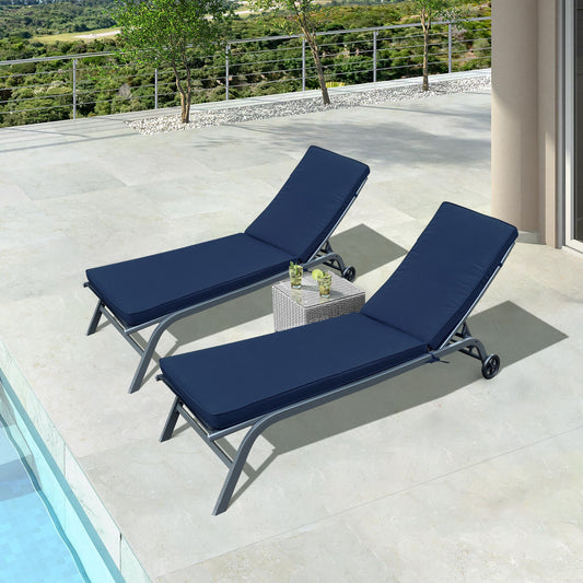 Two Outdoor Lounge Chair Cushion Replacement Patio Furniture Seat Cushions are on a stone patio near a pool, with a small wicker table and two glasses between them. A railing and lush greenery are in the background.