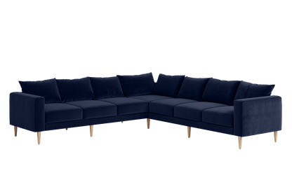 The Essential Corner Sectional (7 Seat) in navy blue velvet, designed as an L-shaped sofa with wooden legs and complete with seat and back cushions, displayed on a white background.