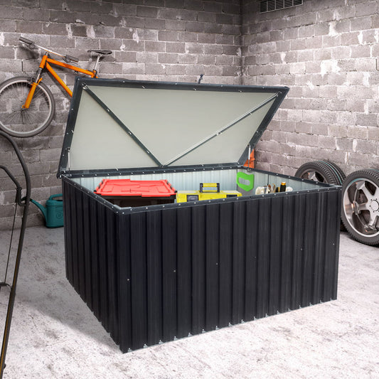 In a concrete garage, the Metal Storage Box Store Large Outdoor Use - Black, holds tools and a red container. A bicycle is mounted on the wall, with spare tires nearby.