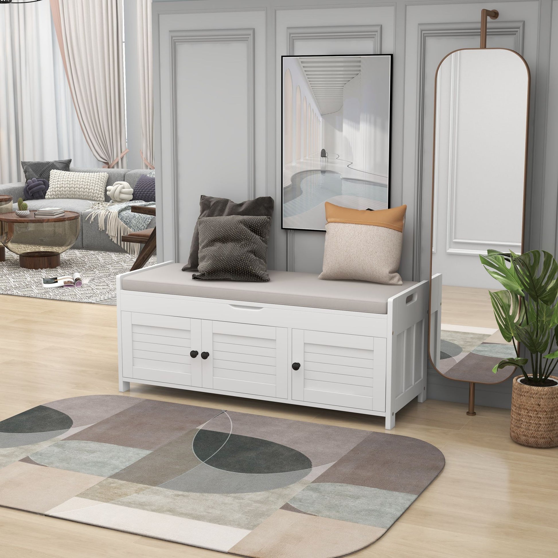 A room features a Storage Bench with shutter-shaped doors and a cushioned seat, next to a full-length mirror. A modern geometric rug adorns the wooden floor, framed by gray paneled walls and a plant. In the background, there's a cozy seating area with pillows and curtains.