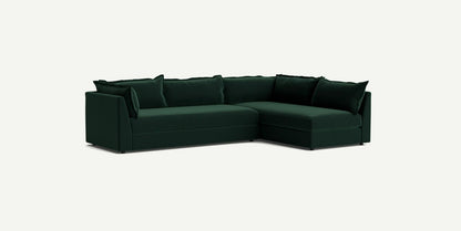 The Denver Two Piece Velvet L Shaped 119" Sectional, in a deep green hue, boasts clean lines and includes several matching cushions, all set against a simple light background.