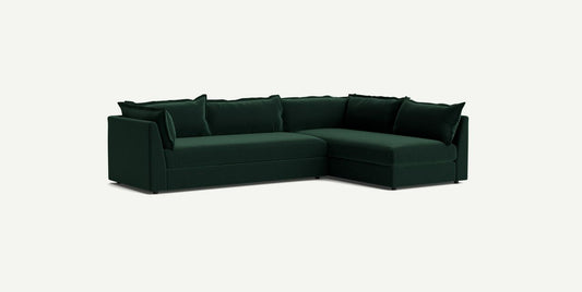 The Denver Two Piece Velvet L Shaped 119" Sectional, in a deep green hue, boasts clean lines and includes several matching cushions, all set against a simple light background.