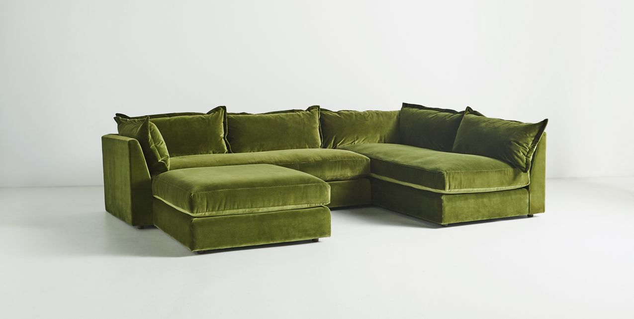 The Denver Two Piece Velvet L Shaped 119" Sectional, upholstered in plush green velvet, is set against a plain white background. It features thick cushions and an L-shaped design, offering a cozy and comfortable appearance.