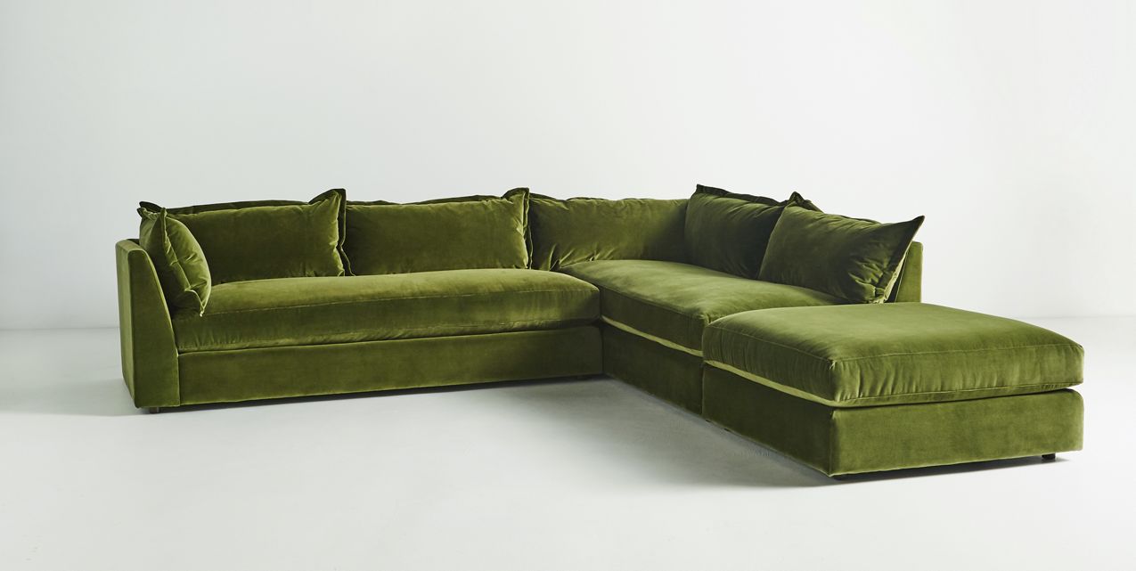 The Denver Two Piece Velvet L Shaped 119" Sectional in a modern green hue, featuring plush cushions, is showcased against a plain white backdrop. Its L-shaped design provides ample seating space.