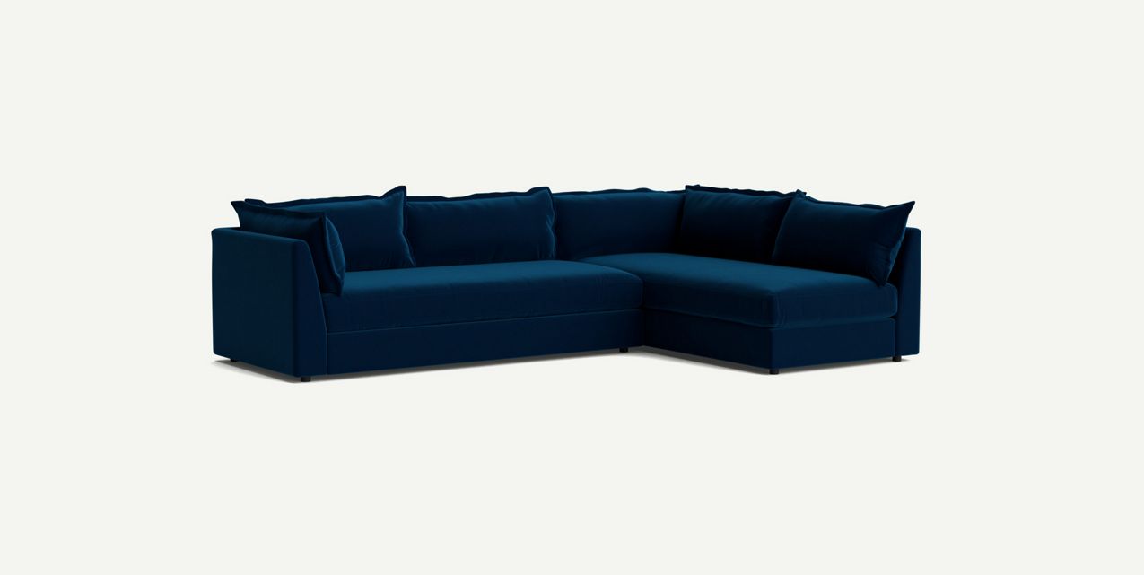 The Denver Two Piece Velvet L Shaped 119" Sectional in modern dark blue features a right-hand chaise and comes with matching cushions, all set against a light background.