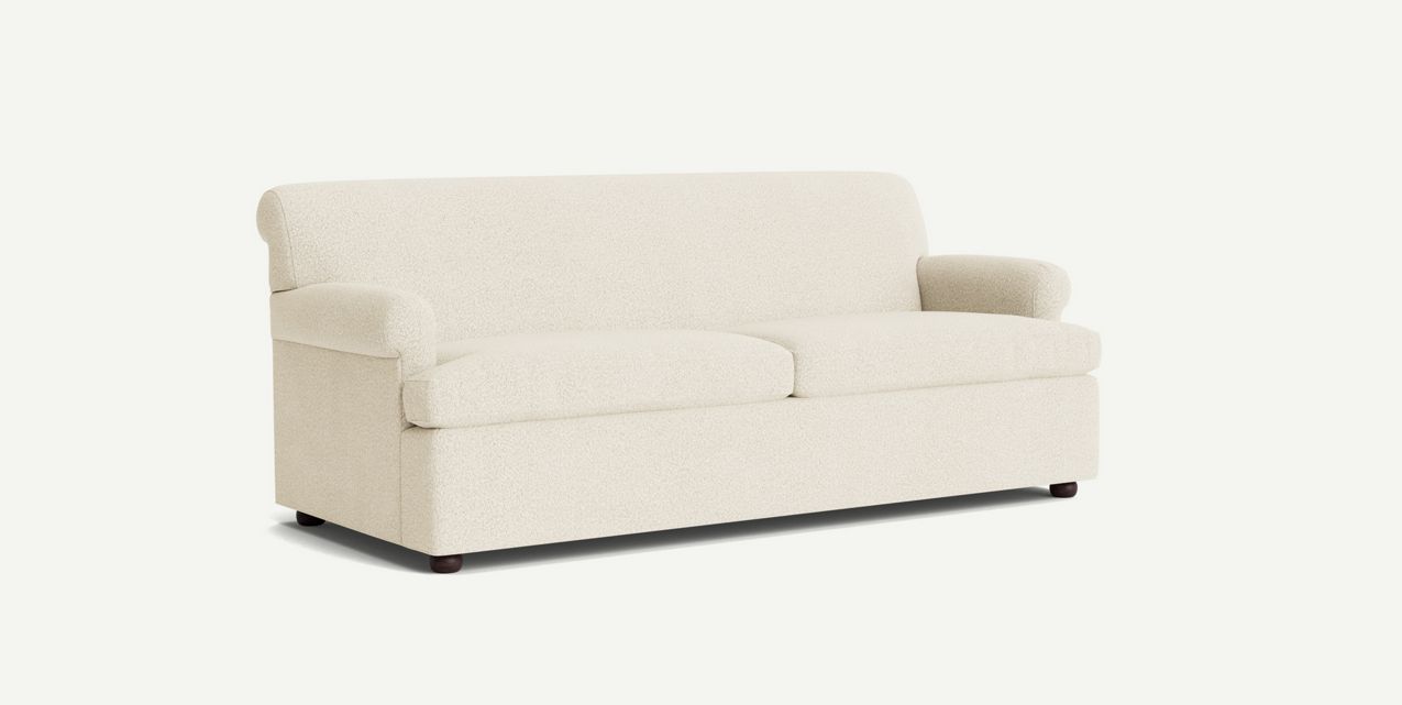 The Willoughby Sleeper Sofa, featuring a cream color, minimalist design, rounded arms, and a plush seat, is elegantly showcased against a plain white background.