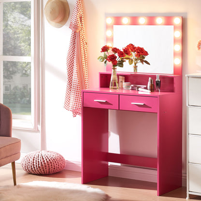 A brightly lit Vanity Desk With Mirror And Lights, featuring a large drawer and 2-tier storage, is decorated with vases of red flowers and cosmetics. Nearby hang a hat and polka dot scarf. Natural light highlights a plush round pink cushion on the floor.