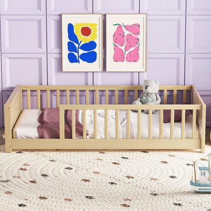 A cozy children's room with a Floor Platform Bed featuring a teddy bear, pink blanket, and white pillow. The wall has a light purple panel and two colorful framed art pieces. A round, textured rug covers the wooden floor.