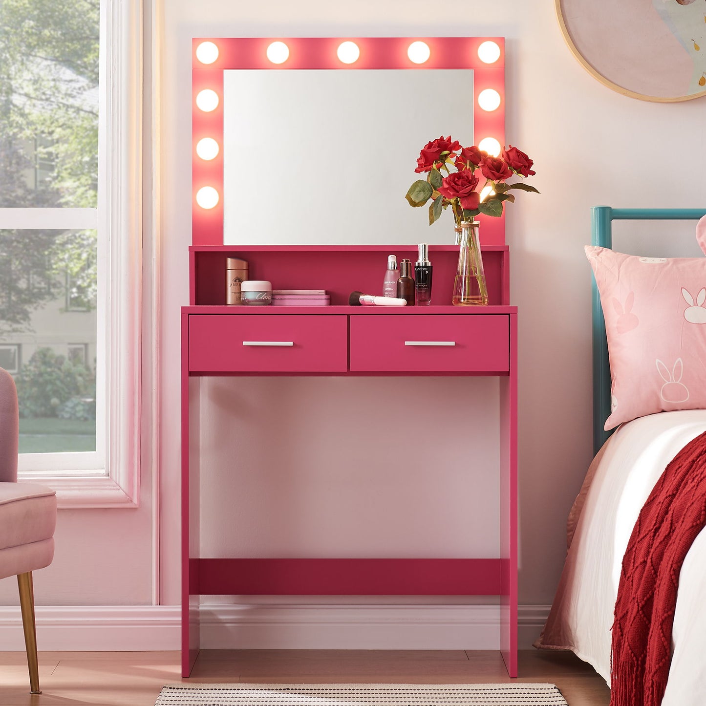 In a pink-themed bedroom, the Vanity Desk with Mirror and Lights, featuring a large drawer and two-tier storage dresser with adjustable lighting modes, is adorned with red roses. Nearby makeup items complement the scene next to a bed with matching pink bedding.