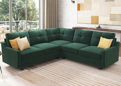 The HONBAY Convertible Sectional Reversible Apartment, an L-shaped green sofa with button-tufted cushions, is beautifully accented by two yellow pillows. It rests on a light-colored rug in a living room featuring large windows, neutral walls, and a minimalist art piece in the background.