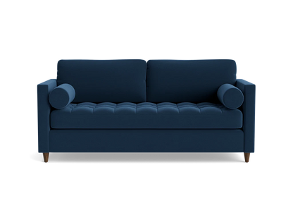 The Briar Sleeper Sofa is a dark blue piece featuring tufted cushions and two round bolster pillows, designed in a modern style with wooden legs that give it a clean, sleek appearance against a black background.