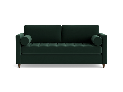 The Briar Sleeper Sofa is a dark green, mid-century modern piece featuring two cylindrical arm cushions and tufted seating. It is elevated on short wooden legs and presented against a plain black background.