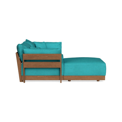 Side view of a sectional couch with teal cushions and a wooden frame. The back and seat cushions are plush, and the design includes a chaise on one end for lounging. The couch is set against a white background.