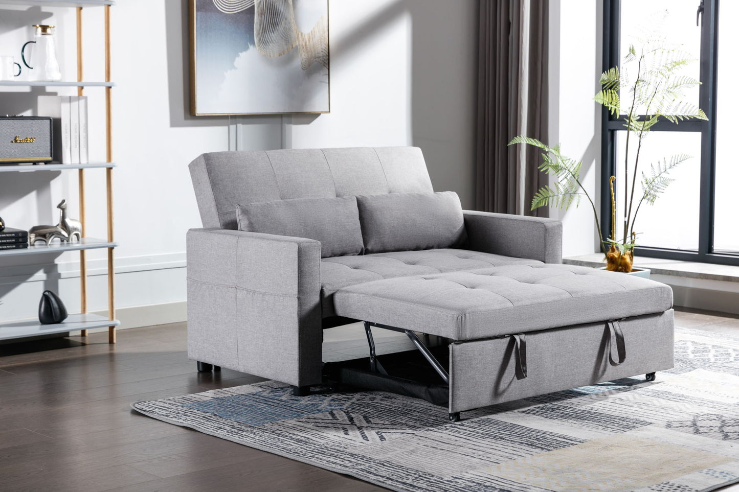 A 2 Seaters Sleeper Sofa Bed in gray linen fabric is extended in a modern living room featuring wooden floors and a large window, accompanied by a left-side bookshelf with decor items, a patterned rug beneath the sofa, and a potted plant near the window.