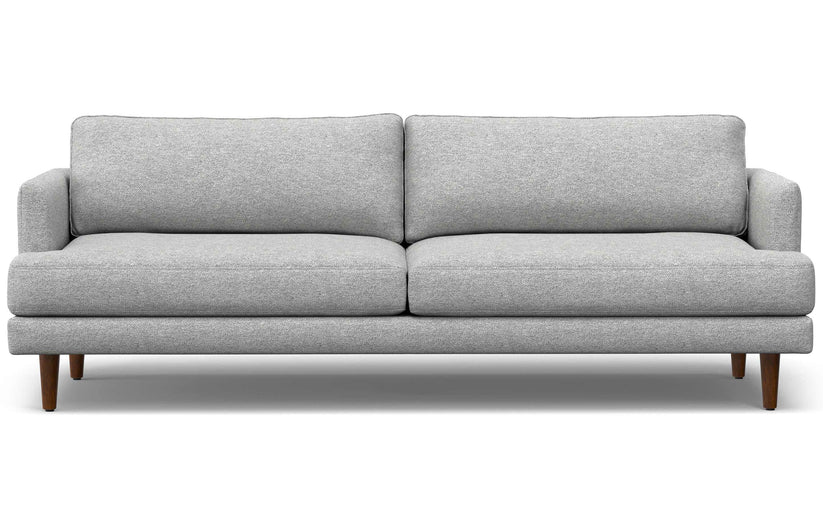 The Livingston 90-Inch Mid Century Sofa is a modern piece featuring clean lines, light gray upholstery, and wooden legs. It includes two seat cushions and two back cushions, embodying a minimalist and contemporary design.