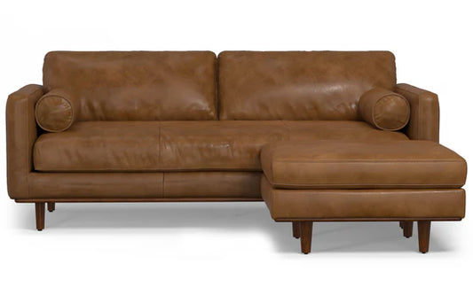 The Morrison 89-Inch Sofa and Ottoman Set in Genuine Leather is a stylish brown leather sofa featuring a right-side chaise, two large back cushions, cylindrical arm pillows, and wooden legs.