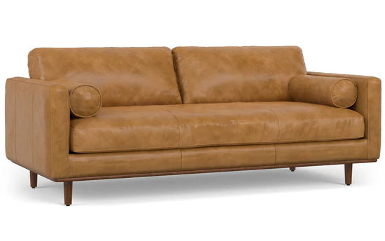 The Morrison 89-Inch Sofa and Ottoman Set in Genuine Leather features two seat cushions and two back cushions, complemented by cylindrical bolster pillows on each side. It stands elegantly on wooden legs.