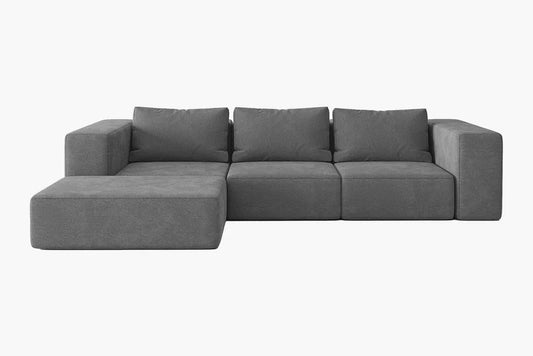 The Atlas Modular Sofa by Acanva is a modern gray sectional with a minimalist design. It features three backrest cushions and a left-side chaise lounge, complemented by blocky armrests, all set against a plain white background.