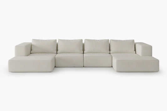 The Atlas Modular Sofa by Acanva is a cream-colored sectional with five cushioned backrests and broad armrests, designed in a minimalist style and set against a plain white background.