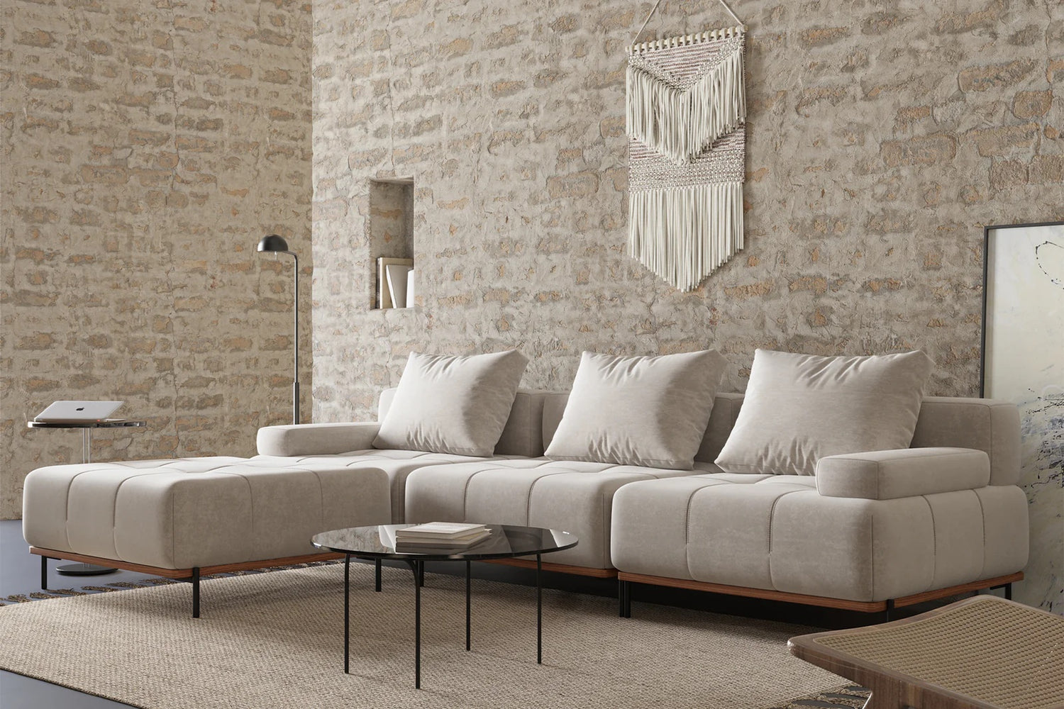 Tan L-Shaped Sectional in a brick room with a black coffee table in front of the sofa. The table has books on top of it. 