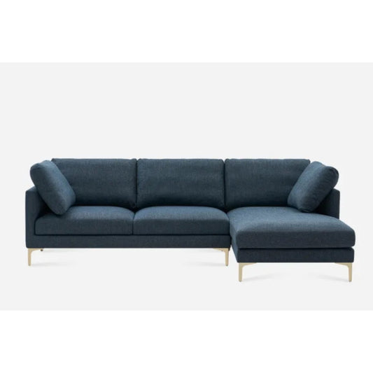 A modern dark gray sectional sofa with an L-shaped design, featuring slim armrests and cushioned back pillows. The sofa has a chaise lounge on the right side and is supported by sleek, thin metal legs. The background is plain white.